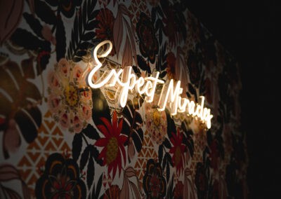 Bright Futures Chiropractic neon sign on floral patterned wall, promoting health and wellness servic.