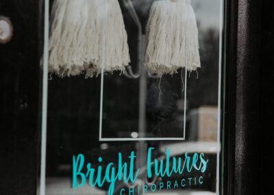 Bright Futures Chiropractic sign with rainbow and tassels on glass door.